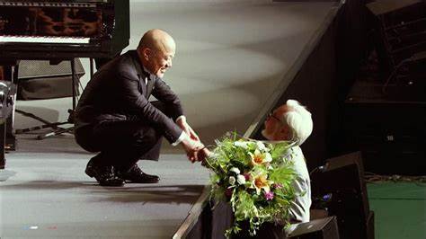 Joe Hisaishi reçoit un bouquet de Hayao Miyazaki au concert des 25 ans du Studio Ghibli à Budokan